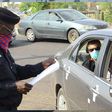A Nigerian police officer checking a vehicle documents at a checkpoint. [Carmart]