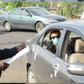 A Nigerian police officer checking a vehicle documents at a checkpoint. [Carmart]