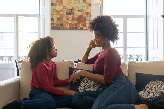A woman holding hands with her daughter while sitting on couch [Photo: Kampus Production]