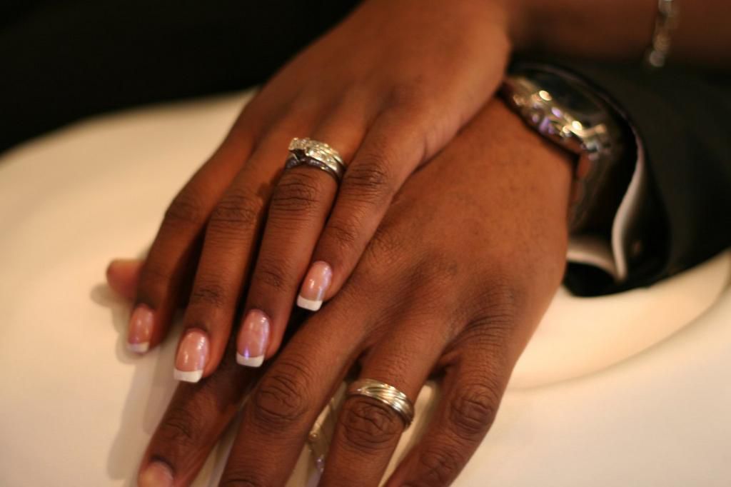 A stock photo of a couple showing off their wedding rings.