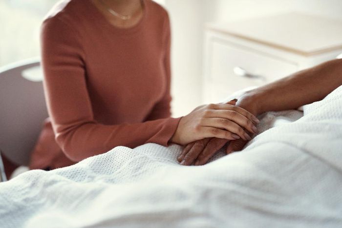 A woman holds a patients hand at a hospital.shapecharge/Getty Images