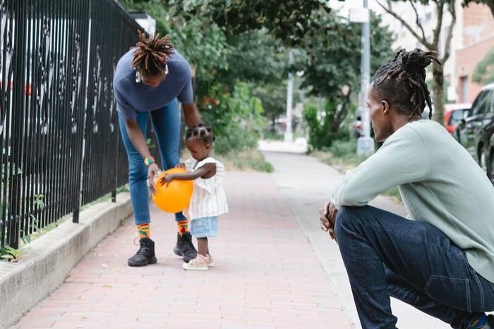 Mum and dad walking with their daughter outside [Image Credit: Greta Hoffman]