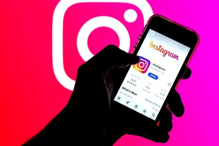 the Instagram app in App Store seen displayed on a smartphone screen and a Instagram logo in the background.