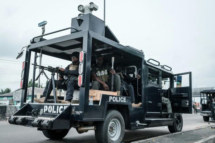 A member of the SWAT police unit straddles a machine gun outside a vote collation centre in Port Harcourt, Nigeria's oil hub