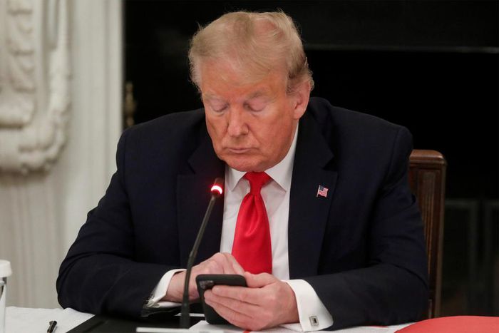 Former President Donald Trump uses a mobile phone during a roundtable discussion on the reopening of small businesses in the State Dining Room at the White House in Washington, US, June 18, 2020.