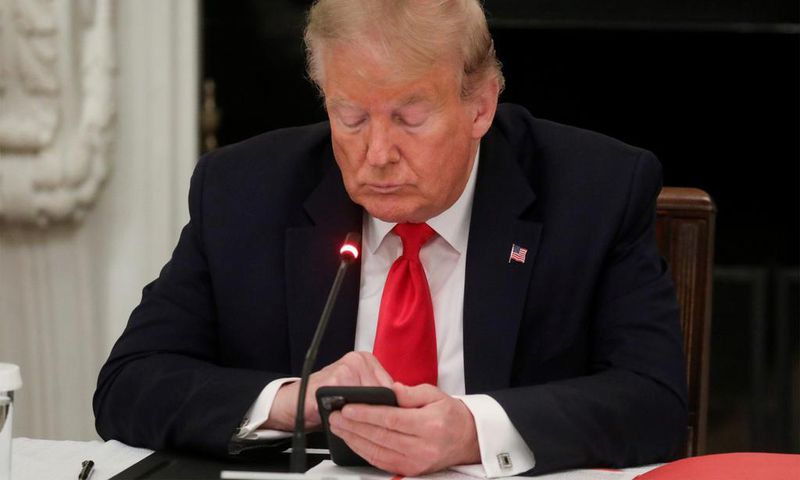 Former President Donald Trump uses a mobile phone during a roundtable discussion on the reopening of small businesses in the State Dining Room at the White House in Washington, US, June 18, 2020.