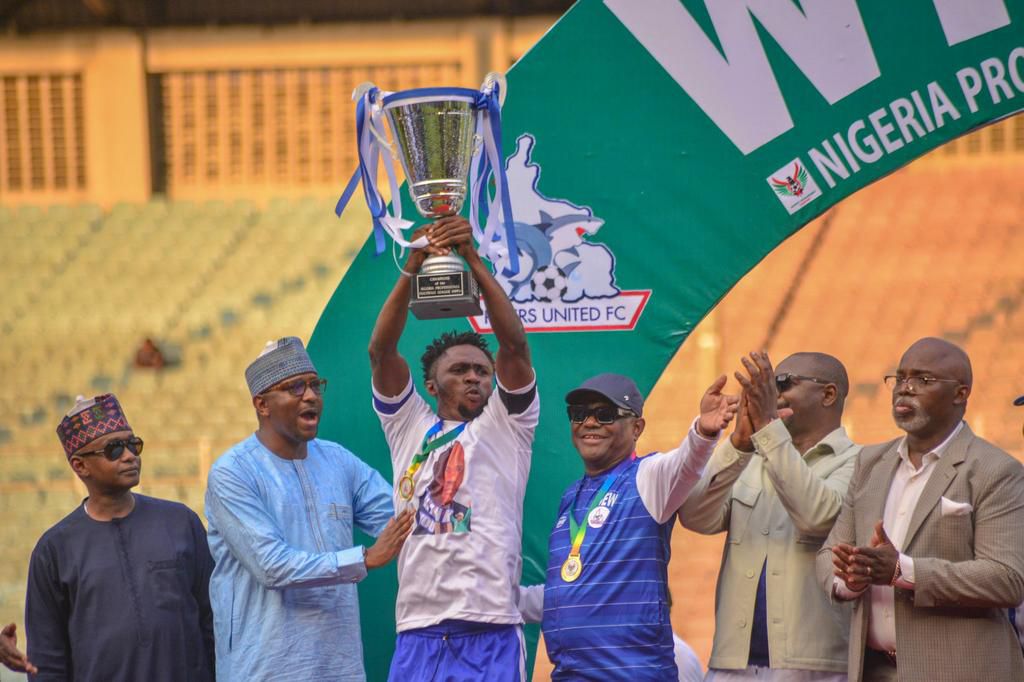 Governor Nyesom Wike (third from right) smiles as Rivers United captain Festus Austine (centre) lifts the NPFL trophy