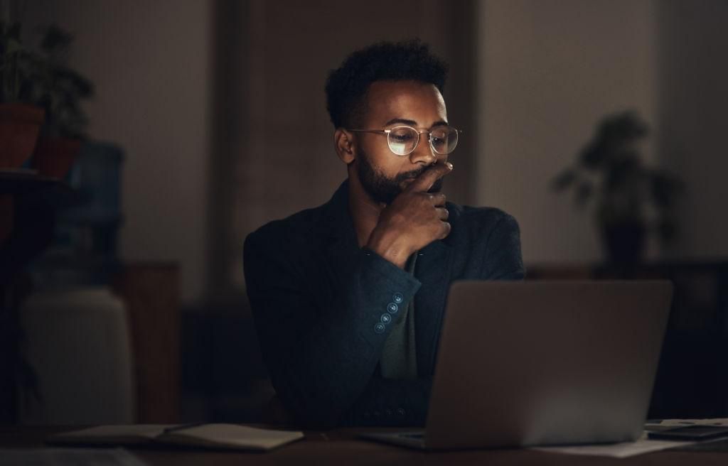 Shot of a young businessman using a laptop during a late night at work