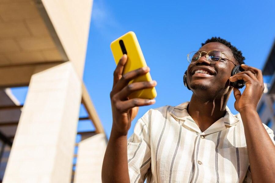 A young man relaxing outdoors listening to music using phone and headphones