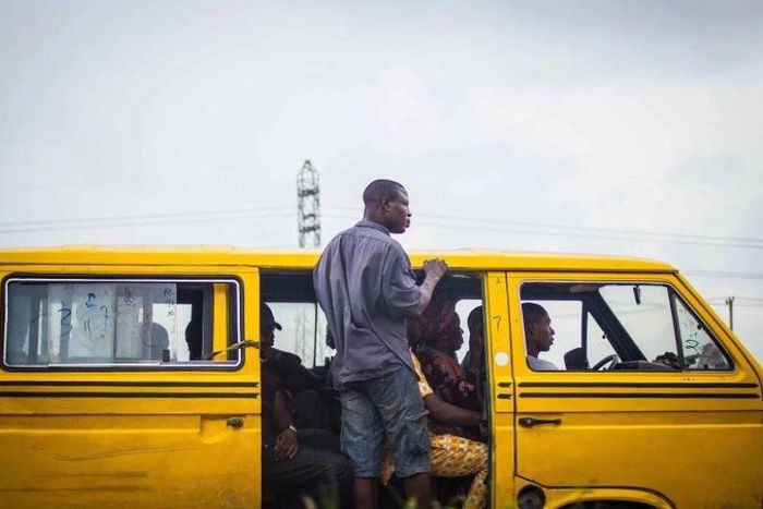 A Lagos 'Danfo' conveying people to their destination, 'Agbero' helps the driver.