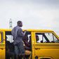 A Lagos 'Danfo' conveying people to their destination, 'Agbero' helps the driver.