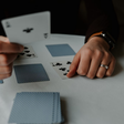 Person holding playing cards on white table