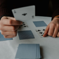Person holding playing cards on white table