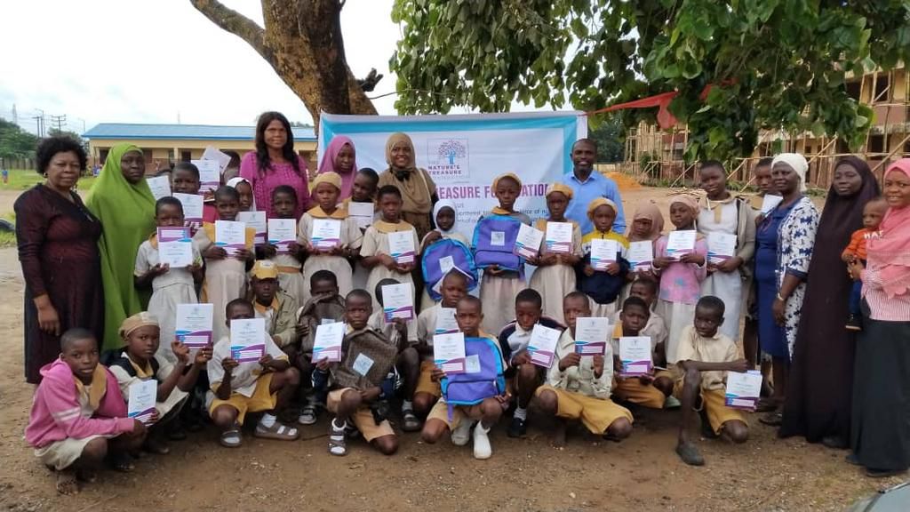 A group photo of the management of one of the beneficiary schools, the campaign facilitators and pupils showing off the educational materials they received from the NGO. [Natures Treasure]
