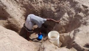 Miss Jennifer Nimfa, a secondary school student, scooping water from one of the ponds in the community. [NAN]