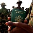 A Nigerian officer holds passports for his troops preparing to board a U.S. military plane in the Nigerian capital of Abuja.