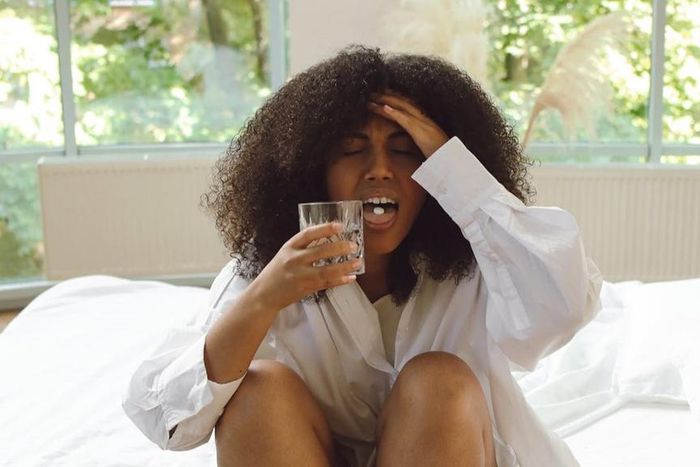 Woman in white long-sleeve shirt sitting on a bed [Image Credit: Polina Tankilevitch]