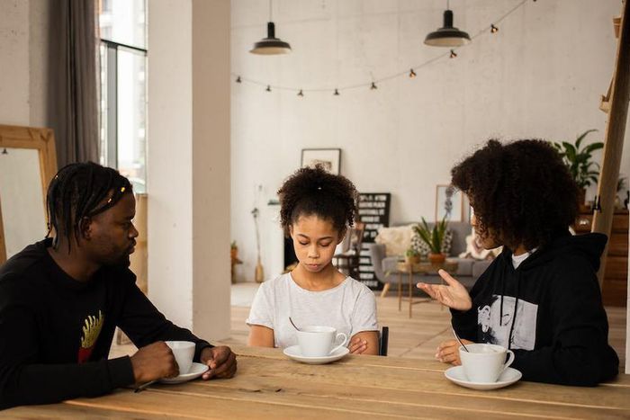Black parents lecturing upset daughter at table [Credit: Monstera Production]