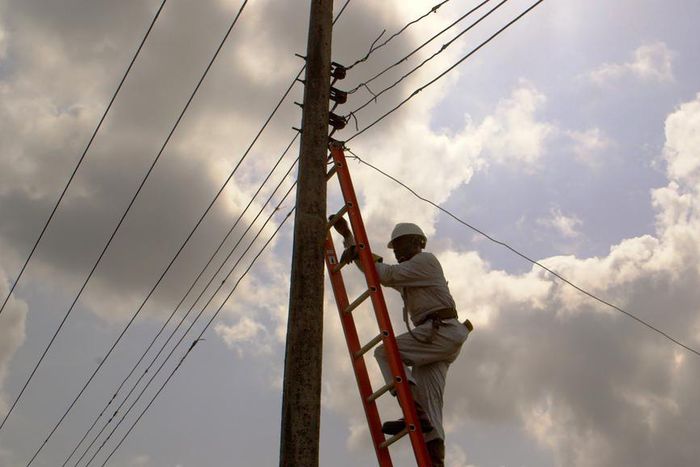 Electricity official climbing a ladder on a pole (image used for illustration) [Africa Is a Country]