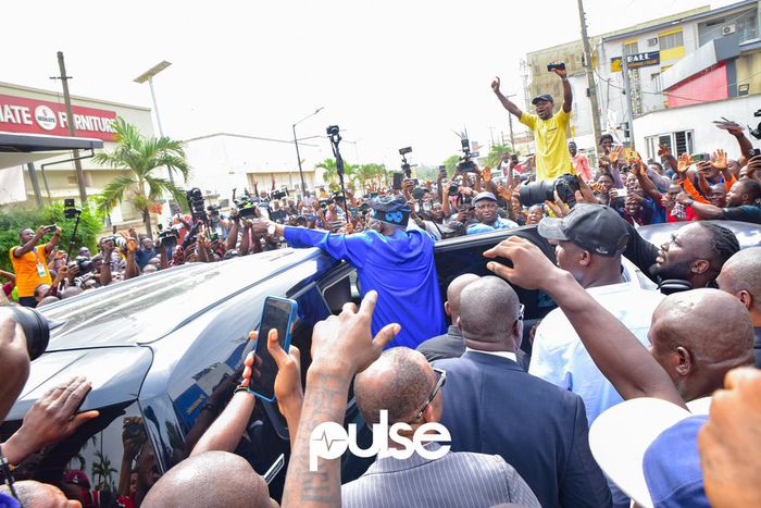 Bola Tinubu (in blue) surrounded by a crowd of supporters at his polling unit in Lagos