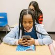 Girl sitting on her desk while using her smartphone [Image: RDNE Stock Project]