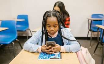 Girl sitting on her desk while using her smartphone [Image: RDNE Stock Project]