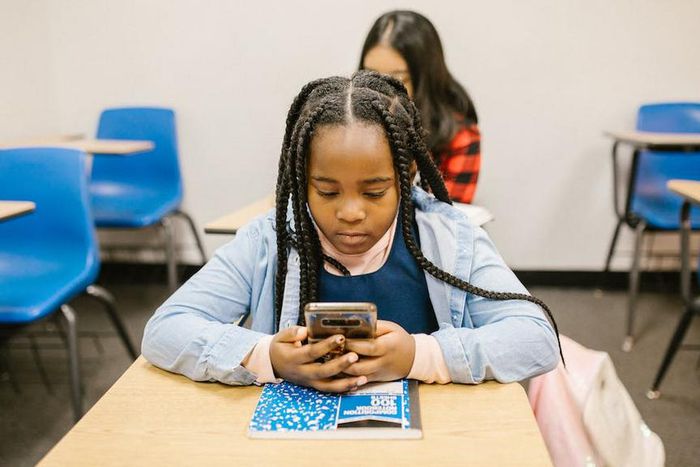 Girl sitting on her desk while using her smartphone [Image: RDNE Stock Project]
