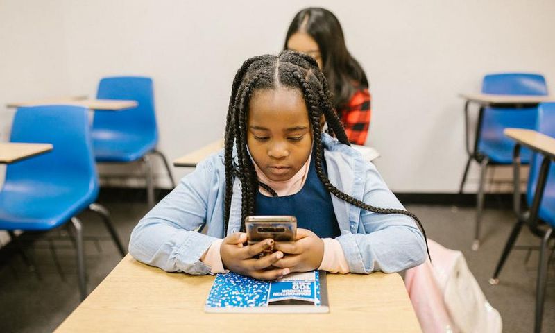 Girl sitting on her desk while using her smartphone [Image: RDNE Stock Project]