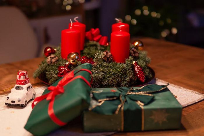 Unlighted red advent candles on a table beside green gift boxes [Credit: Alex Fu]