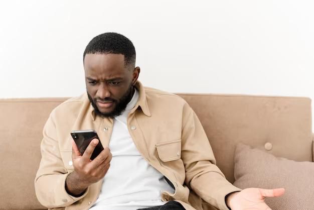 Black man angry at phone (image used for illustration) [Freepik]