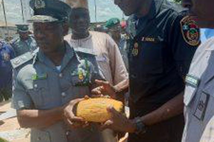 The Controller, Seme Area Command of Nigeria Customs Service, Comptroller Dera Nandi, handing over 553 parcels of cannabis sativa seized by his men to Mr Abubakar Wada, the Commander, National Drugs Law Enforcement Agency (NDLEA) on Wednesday in Semé.