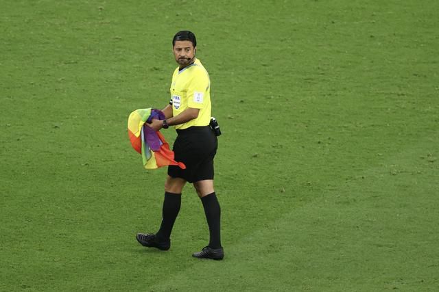 Referee Alireza Faghani removes the pitch invader’s rainbow flag