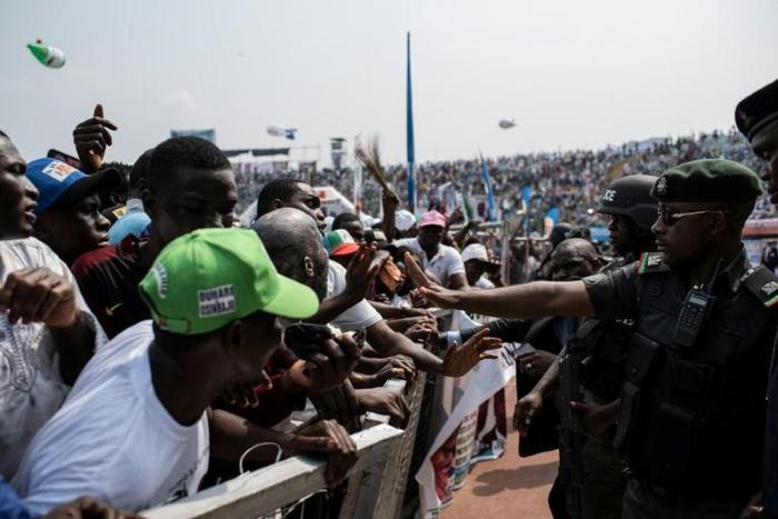 Security personnel control a crowd of supporters of Nigeria's ruling All Progressive Congress (APC) party at a stadium campaign rally in Lagos