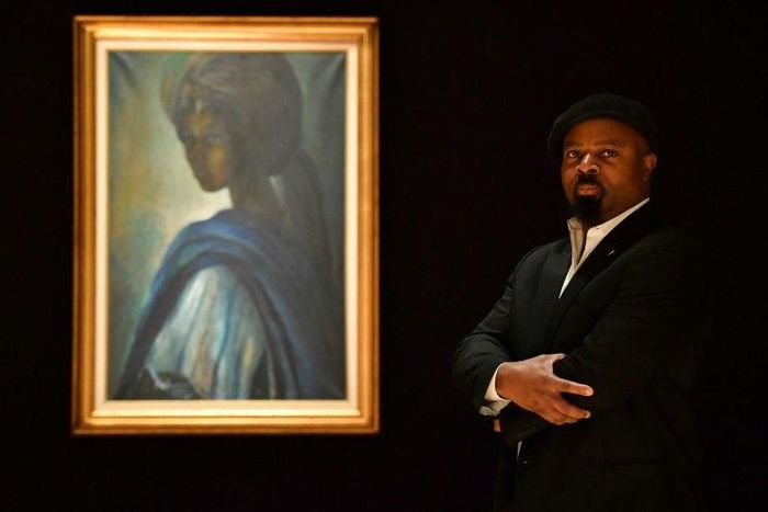 Nigerian author Ben Okri poses with a work of art by Nigerian painter and sculptor Ben Enwonwu entitled 'Tutu', the "African Mona Lisa" sold at auction in London for £1.2 million (1.4 million euros, $1.7 million), setting a record for the artist