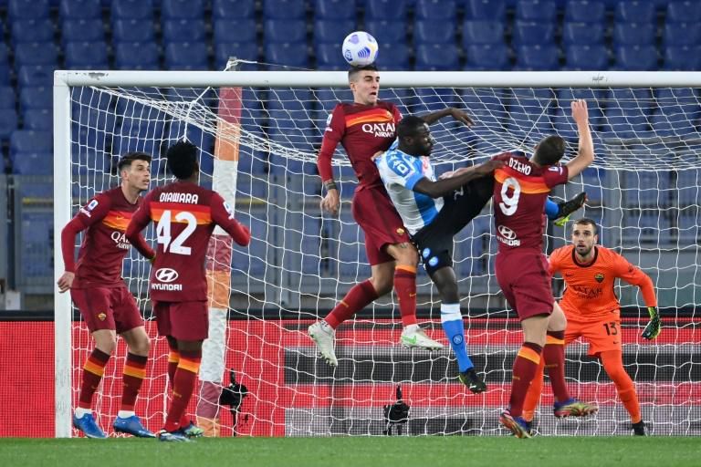 Napoli defender Kalidou Koulibaly (C) is surrounded by Roma players in a Serie A aerial duel.