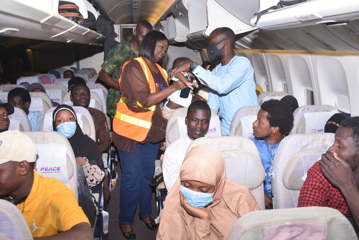 Nigerian evacuees with Chairman/ CEO of Nigerians in Diaspora Commission (NiDCOM) Abike Dabiri-Erewa (middle) during their evacuation back to Nigeria. [Guardian]