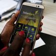 A customer uses her cell-phone to access the Sidian Bank mobile-app inside the banking hall at the Sidian Bank headquarters on the outskirts of Kenya's capital Nairobi, June 29, 2016. Picture taken June 29, 2016.