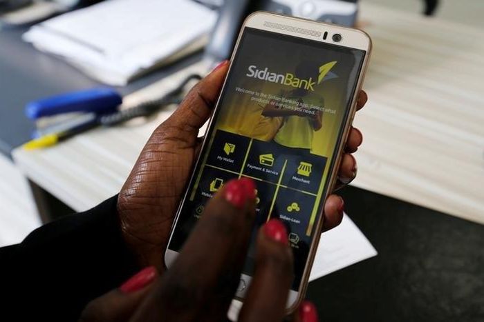 A customer uses her cell-phone to access the Sidian Bank mobile-app inside the banking hall at the Sidian Bank headquarters on the outskirts of Kenya's capital Nairobi, June 29, 2016. Picture taken June 29, 2016.