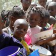 A stream of children wait in line during a food distribution at a feeding centre. [Getty Images]