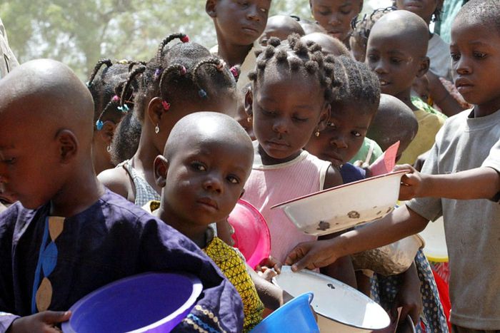 A stream of children wait in line during a food distribution at a feeding centre. [Getty Images]