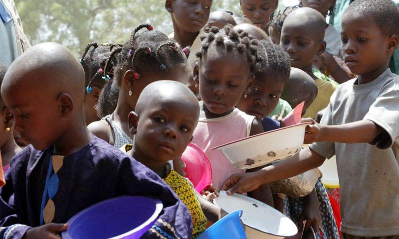 A stream of children wait in line during a food distribution at a feeding centre. [Getty Images]