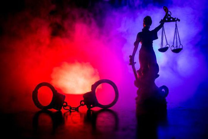A pair of handcuffs and Lady Justice (image used for illustrative purpose) [Adobe Stock]