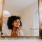 A Black woman looking in the mirror [Glamour]