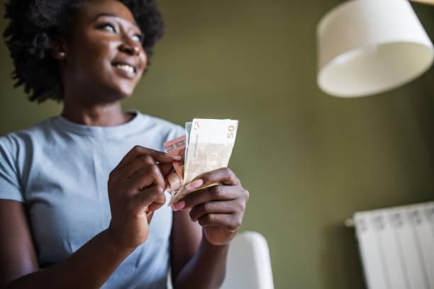 A woman at home counting money. Photo credits: Riska