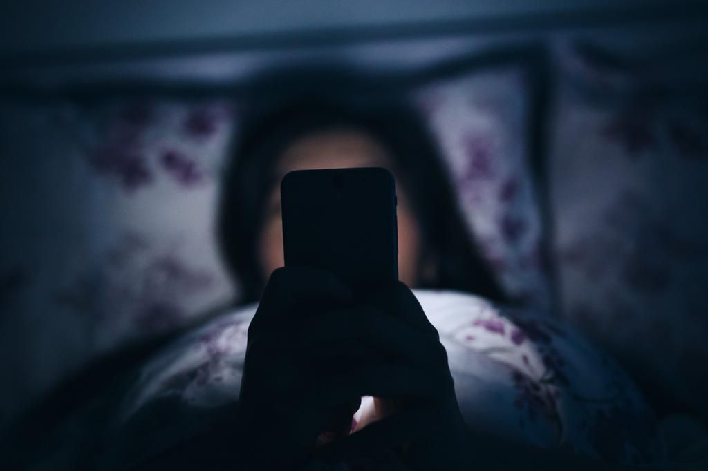 Woman reading and texting on smartphone in bed.Yiu Yu Hoi/Getty Images
