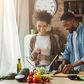 Laughing black couple preparing salad in kitchen