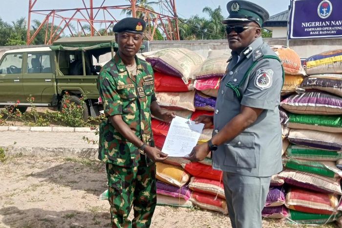 Lt Cdr. Bitus Zoaka, the Base Operating Officer, representing the Commanding Officer, Forward Operating Base of Nigerian Navy, Badagry hands over papers and unspecified number of foreign rice seized by the command to DC ID Musa, the Officer in Charge o...