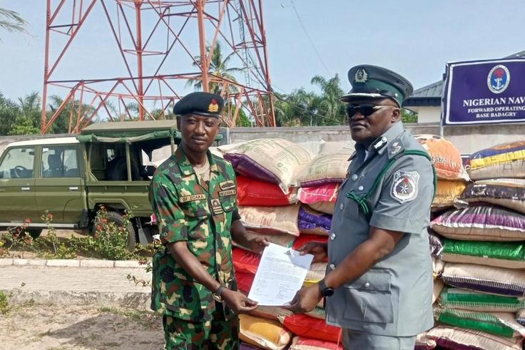Lt Cdr. Bitus Zoaka, the Base Operating Officer, representing the Commanding Officer, Forward Operating Base of Nigerian Navy, Badagry hands over papers and unspecified number of foreign rice seized by the command to DC ID Musa, the Officer in Charge o...