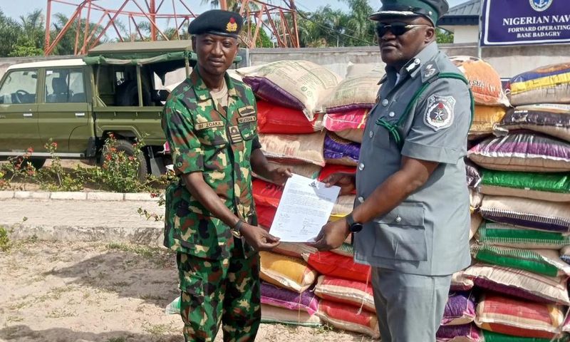 Lt Cdr. Bitus Zoaka, the Base Operating Officer, representing the Commanding Officer, Forward Operating Base of Nigerian Navy, Badagry hands over papers and unspecified number of foreign rice seized by the command to DC ID Musa, the Officer in Charge o...