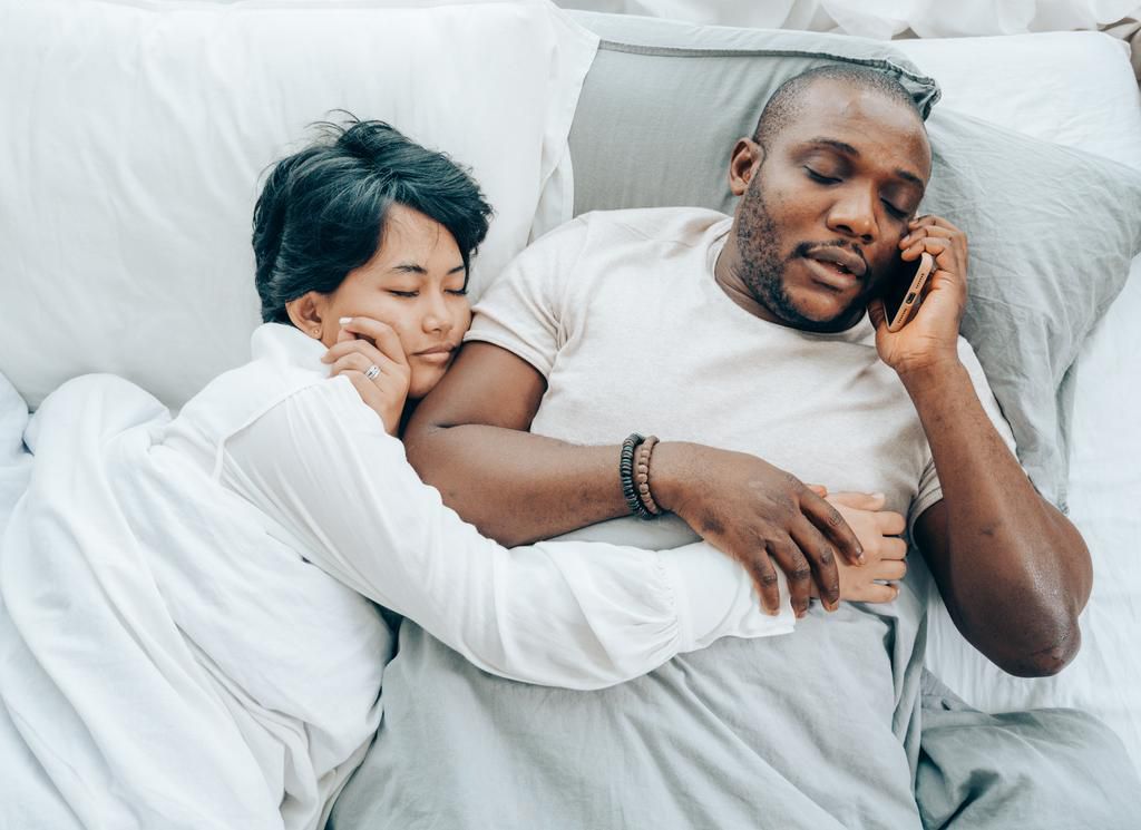 Man speaking on phone next to a sleeping lady